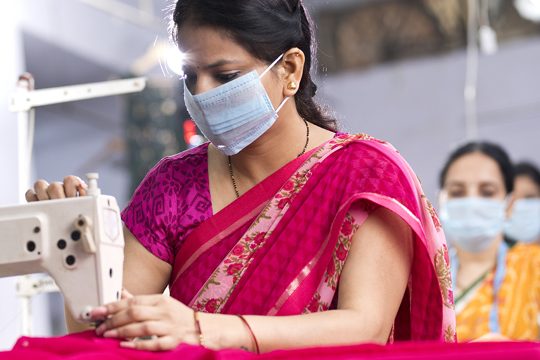 Indian woman textile workers with protective face mask on production line