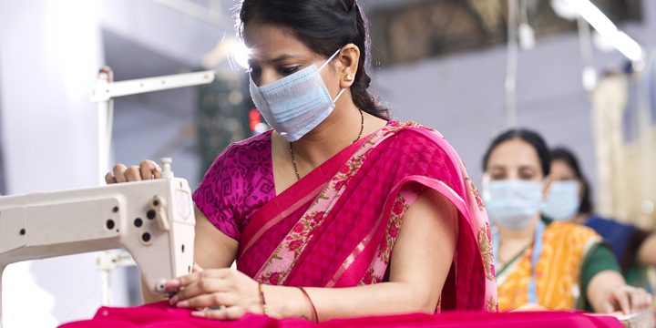 Indian woman textile workers with protective face mask on production line