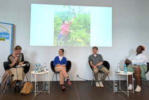 Elisabeth Weydt liest eine Passage aus ihrem Buch. Im Hintergrund ein Bild von Cenaida Guachagmira, einer ecuadorianischen Aktivistin. Foto: Fair Trade Stadt Hamburg